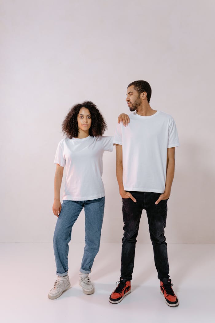 Two young adults posing in casual blank t-shirts, holding a relaxed and confident stance.